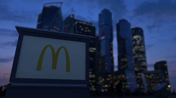 Segnavia stradale con logo McDonalds la sera. Sfondo sfocato grattacieli quartiere degli affari. Rendering editoriale 3D — Foto Stock