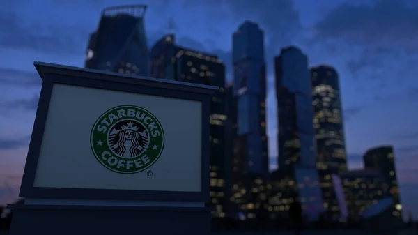 Pouliční nápisy deska s Starbucks logo ve večerních hodinách. Obchodní čtvrť mrakodrapů pozadí rozmazané. Úvodník 3d vykreslování — Stock fotografie