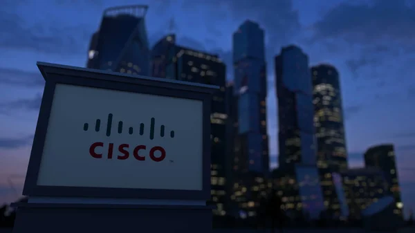 Tablero de señalización con el logotipo de Cisco Systems por la noche. Rascacielos distritos de negocios borrosa fondo. Representación Editorial 3D — Foto de Stock