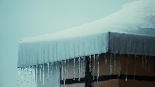 Icicles e coberturas inclinadas nevadas de casas residenciais no inverno 4K racking foco tiro — Vídeo de Stock