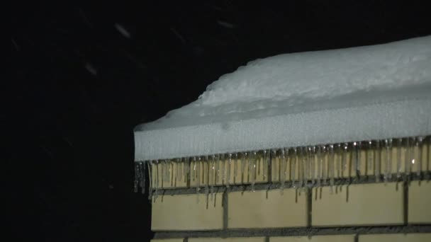 Icicles on the roof of brick building and snowfall at night 4K shot — Stock Video