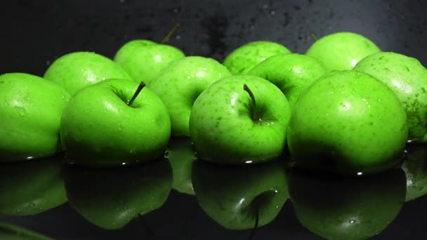 Manzanas verdes en el agua contra fondo negro 4K disparo — Vídeo de stock