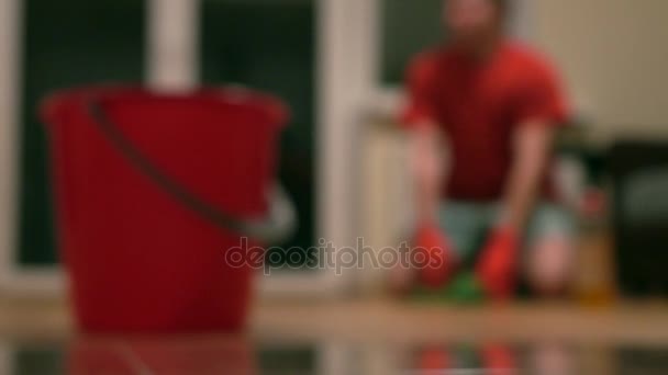 Hombre borroso en camiseta roja limpiando la habitación. Tiro bokeh 4K — Vídeos de Stock