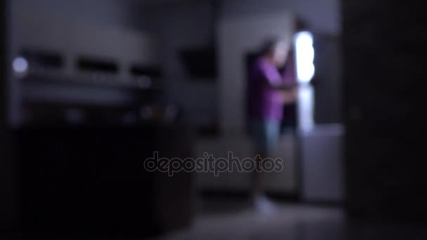 Hombre desenfocado abriendo refrigerador en cocina oscura. Conceptos de glotonería o sobrepeso. Vídeo 4K — Vídeo de stock