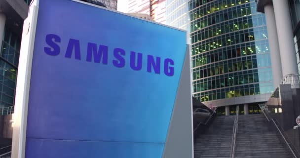 Tablero de señalización con el logotipo de Samsung. Rascacielos moderno centro de oficina y escaleras de fondo. Representación editorial 4K 3D — Vídeos de Stock