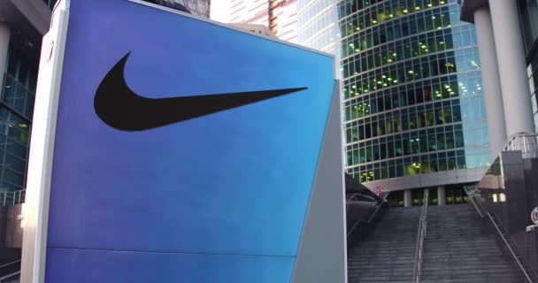 Pouliční nápisy deska s logem Nike. Moderní kancelářské centrum mrakodrap a schody pozadí. Úvodník 4k 3d vykreslování — Stock video