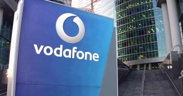 Oznakowanie ulicy deska z Vodafone logo. Nowoczesne biuro centrum drapacz chmur i schody tło. Redakcji 4k renderowania 3d — Wideo stockowe