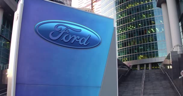 Papan nama jalan dengan logo Ford Motor Company. Gedung kantor modern pencakar langit dan tangga latar belakang. Penyuntingan 4K 3D render — Stok Video