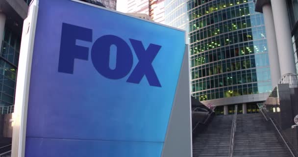 Street Signage Board med Fox Broadcasting företagets logotyp. Modern kontorscenter skyskrapa och trappor bakgrund. Redaktionell 4K 3D-rendering — Stockvideo