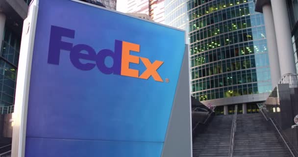 Tablero de señalización con logotipo de FedEx. Rascacielos moderno centro de oficina y escaleras de fondo. Representación editorial 4K 3D — Vídeos de Stock