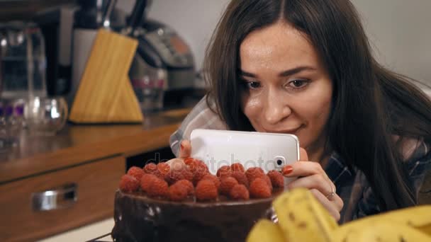 Linda chica morena haciendo fotos y videos de su pastel de frambuesa recién cocinado. Cocina amateur, pastelería casera y concepto de compartir en redes sociales. 4K steadicam tiro — Vídeos de Stock