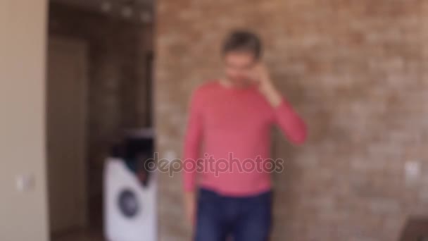 自宅に彼の携帯電話で話しているピンクの t シャツの陽気な男。4 k をステディカム ショットを閉じる — ストック動画