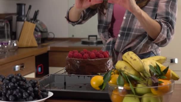 Mujer joven morena haciendo fotos de su pastel de chocolate y frambuesa. Steadicam 4K video — Vídeo de stock