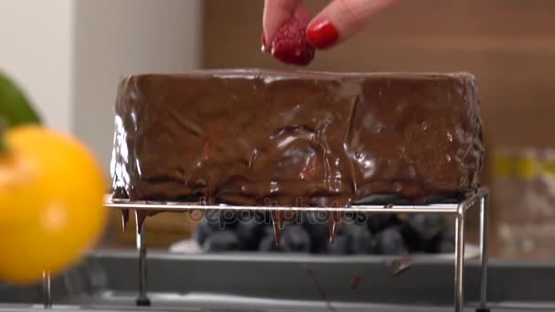Красивая женщина руки размещения малины на свежеприготовленный шоколадный торт. 4K крупным планом видео — стоковое видео