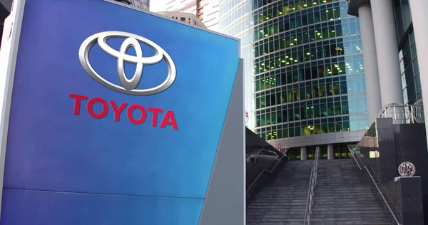 Straßenschildertafel mit Toyota-Logo. modernes Bürozentrum Wolkenkratzer und Treppe Hintergrund. redaktionelles 3D-Rendering — Stockfoto