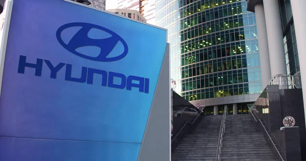 Tablero de señalización con el logotipo de Hyundai Motor Company. Rascacielos moderno centro de oficina y escaleras de fondo. Representación Editorial 3D — Foto de Stock