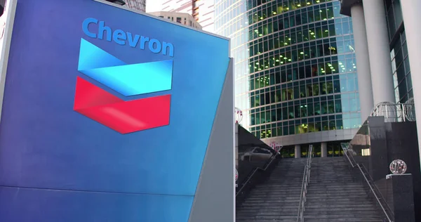 Tablero de señalización con el logotipo de Chevron Corporation. Rascacielos moderno centro de oficina y escaleras de fondo. Representación Editorial 3D — Foto de Stock