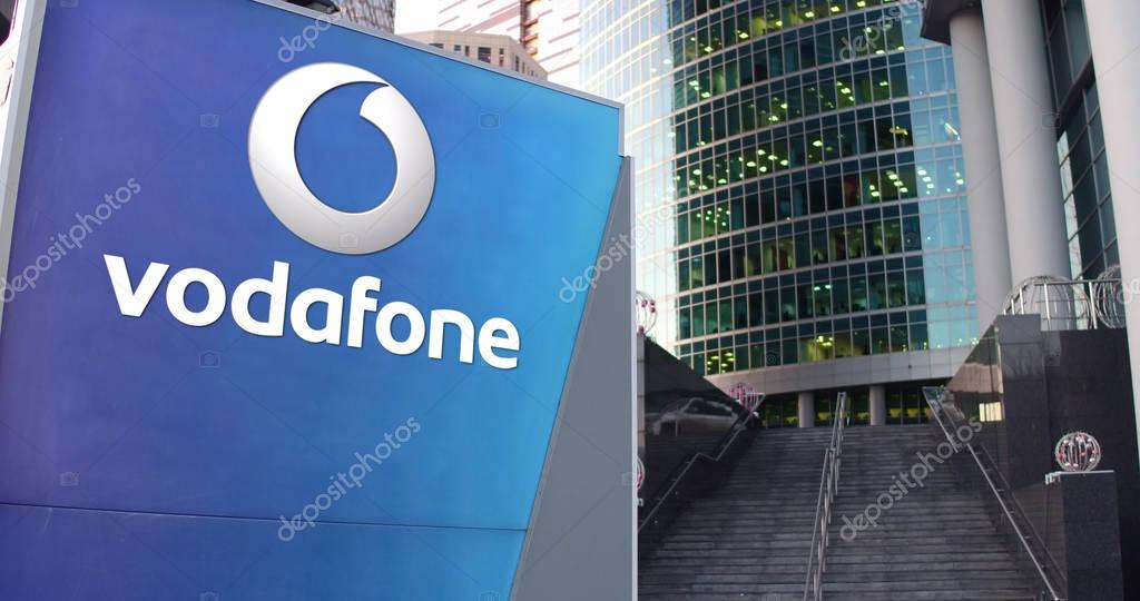 Street signage board with Vodafone logo. Modern office center skyscraper and stairs background. Editorial 3D rendering United States