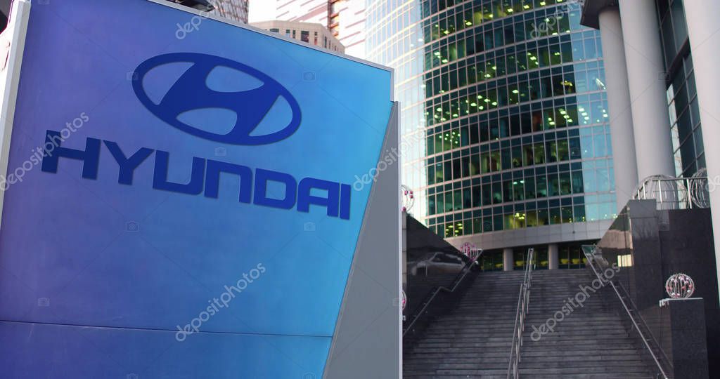 Street signage board with Hyundai Motor Company logo. Modern office center skyscraper and stairs background. Editorial 3D rendering United States