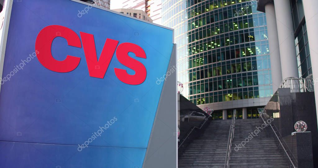 Street signage board with CVS Health logo. Modern office center skyscraper and stairs background. Editorial 3D rendering United States