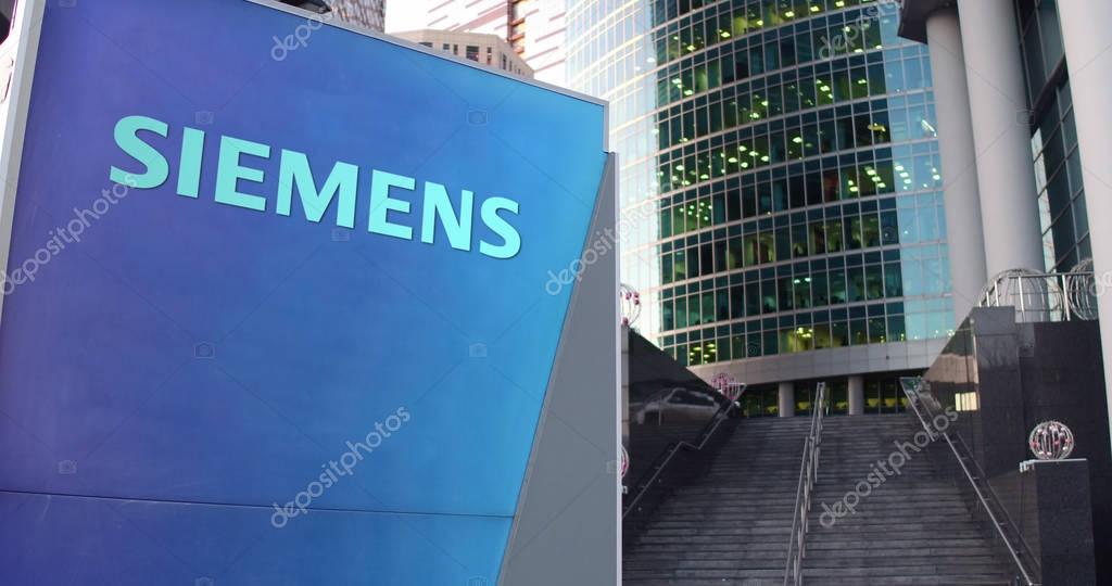 Street signage board with Siemens logo. Modern office center skyscraper and stairs background. Editorial 3D rendering United States