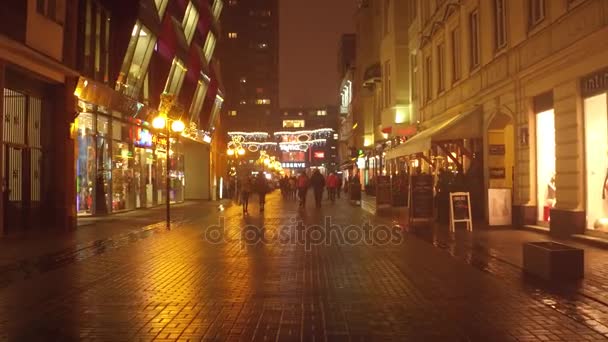 WARSAW, POLOGNE - 28 NOVEMBRE 2016. Le soir, les gens passent devant des cafés et des magasins de rue éclairés. Décorations de Noël. Ville européenne 4K steadicam vidéo — Video