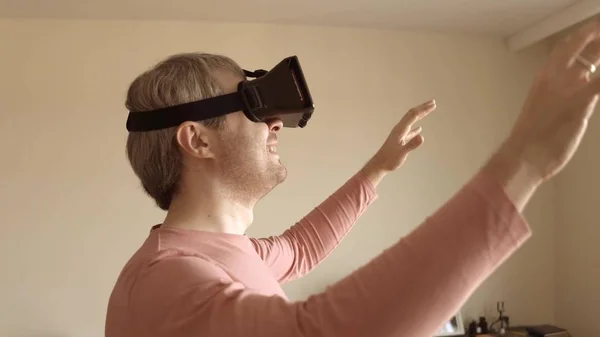 Uomo caucasico divertirsi con il suo cellulare VR auricolare a casa. Maschera realtà virtuale in azione — Foto Stock