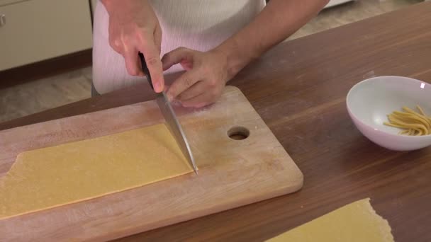 Man cutting homemade pasta with a knife. Amateur cooking at home. 4K steadicam video — Stock Video
