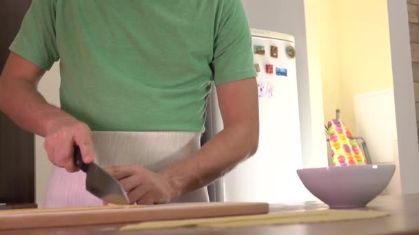 Uomo che taglia pasta fatta in casa con un coltello. Cucina amatoriale a casa. 4K steadicam shot — Video Stock