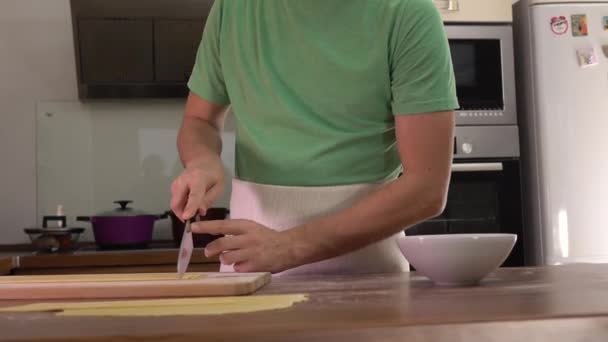 Homme en vert coupant des pâtes maison avec un couteau. Cuisine amateur à la maison. Vidéo 4K steadicam — Video