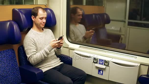 幸せな男は、電車の中彼のスマート フォンにメッセージを入力します。現代の無線通信技術。4 k ビデオ — ストック動画