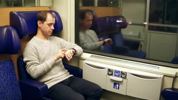Un hombre usando su reloj inteligente en un tren. Tecnología moderna de dispositivos portátiles. Vídeo 4K — Vídeo de stock