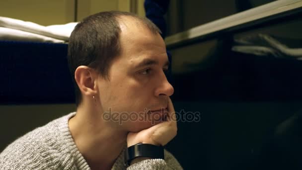 Zamyšlený holohlavý muž s náušnicí cestování vlakem v noci. 4k video — Stock video