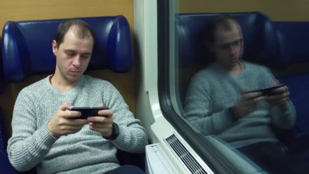 Hombre jugando en su teléfono inteligente en un tren. Vídeo 4K — Vídeos de Stock