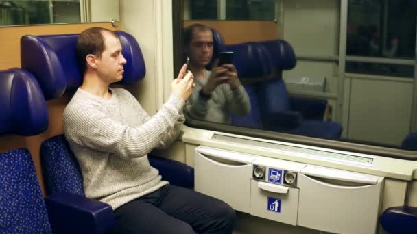 L'uomo che fa foto con il suo smartphone su un treno e lo manda. Video 4K — Video Stock