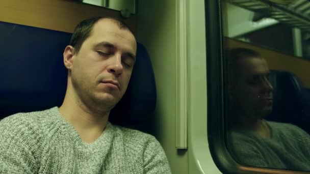 Un uomo con un maglione che dorme sul sedile di un treno. Video 4K — Video Stock