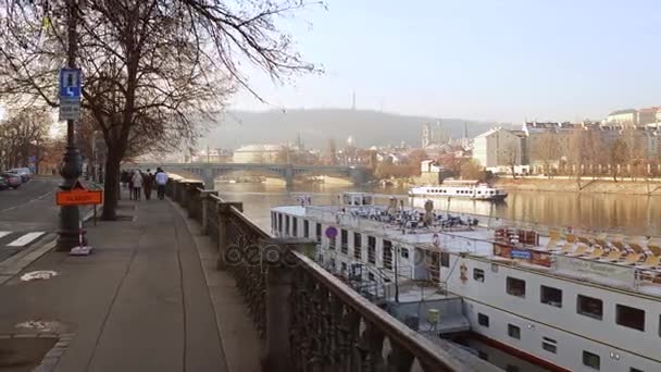 プラハ, チェコ共和国 - 2016 年 12 月 3 日。ヴルタヴァ川観光船と晴れた日に遠くのプラハ城の 4 k のステディカム ショット。街の人気のある観光場所 — ストック動画
