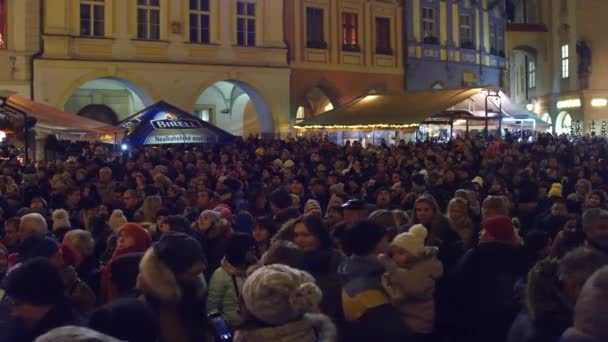 PRAGA, REPÚBLICA CHECA - 3 DE DICIEMBRE DE 2016. 4K pan sobre la cabeza de tiro de la concurrida plaza del casco antiguo por la noche. Turistas haciendo fotos de lugares emblemáticos - Reloj astronómico — Vídeos de Stock