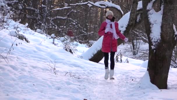 Karlı kış ormandaki kameraya doğru çalışan kırmızı ceketli güzel mutlu kız yavaş çekim — Stok video