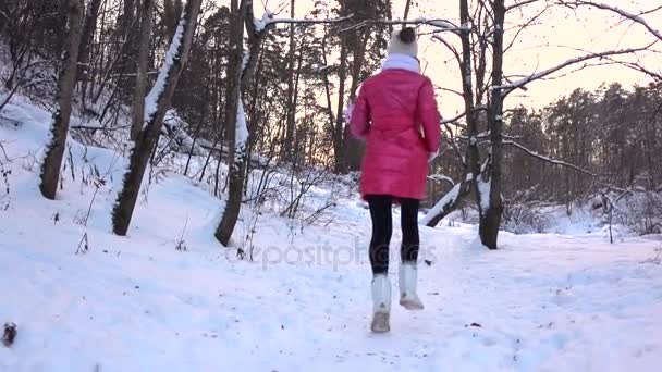 Медленное видео с девочкой в красной куртке, бегущей от камеры в зимнем лесу — стоковое видео