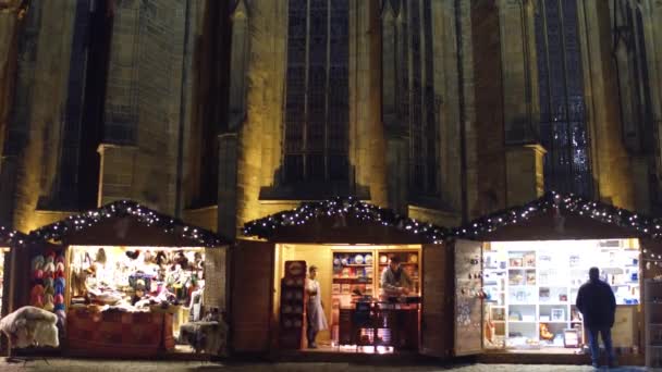 Prague, Tsjechië - 3 December 2016. Kerst bazar cabines in de buurt van Saint Vitus kathedraal in de nacht. De grootste en belangrijkste kerk in het land. 4k kantelen schot — Stockvideo