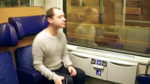 Ein Mann im Pullover nimmt am Bahnhof in einem Zug Platz. 4k-Video — Stockvideo