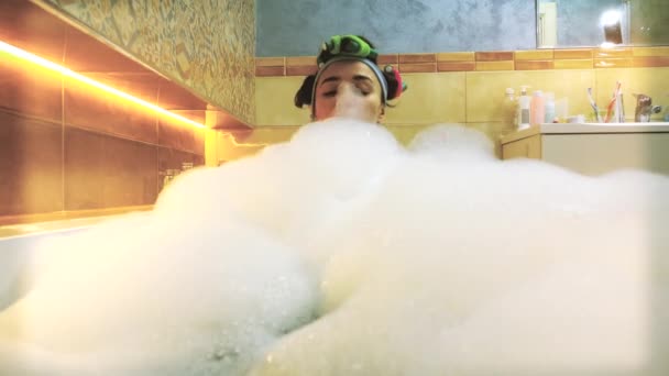Hermosa mujer morena tomando baño espumoso y jugando con espuma de jabón. Vídeo 4K — Vídeo de stock