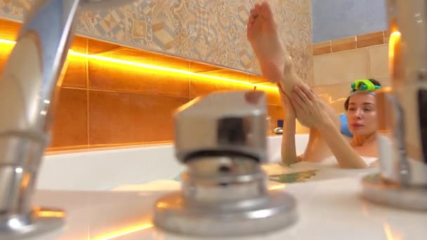 Glad brunett kvinna tar skummande bad och scrubs sitt ben. 4k sköt — Stockvideo