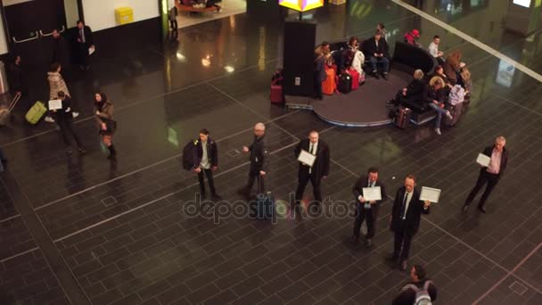 Wien, Österreich - Dezember, 24 steadicam Aufnahme des Ankunftsbereichs des Flughafenterminals und Treffen mit Personen mit Kennzeichen. 4k-Video, Blick von oben — Stockvideo