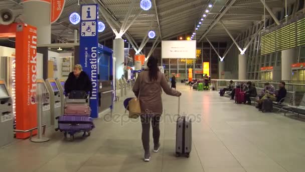 Warsaw, Polen - 24 December, Steadicam schot van vrouwelijke passagier op de luchthaven terminal inchecken gebied. 4k video — Stockvideo