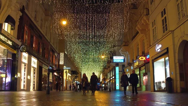 Wiedeń, Austria - 24 grudnia, Boże Narodzenie urządzone wyłączonej z ruchu kołowego ulicy w godzinach wieczornych. Popularne miejsce turystyczne z luksusowe sklepy i Kawiarnie — Zdjęcie stockowe