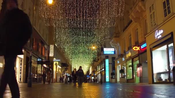 VIENNA, AUSTRIA - 24 DICEMBRE Scatto steadicam ad angolo basso di strada pedonale decorata di Natale la sera. Luogo turistico popolare con negozi di moda di lusso e caffè. Clip 4K — Video Stock