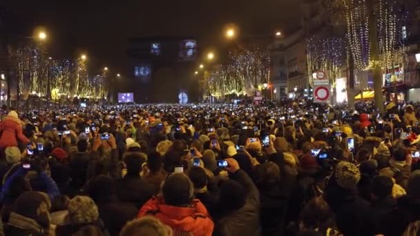 PARÍS, FRANCIA - DICIEMBRE, 31. Cuenta atrás de año nuevo y fuegos artificiales sobre el famoso arco triunfal, Arco del Triunfo. Los turistas grabando videos y filmando fotos con sus teléfonos móviles. Vídeo 4K — Vídeo de stock