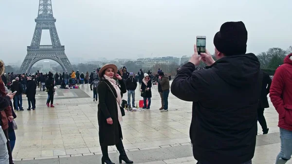 Paris, Frankrike -, 31 December 2016. Vacker ung kvinna som bär hatt poser nära Eiffeltornet på en dimmig dag. De mest populära franska landmärke och turistdestinationen — Stockfoto